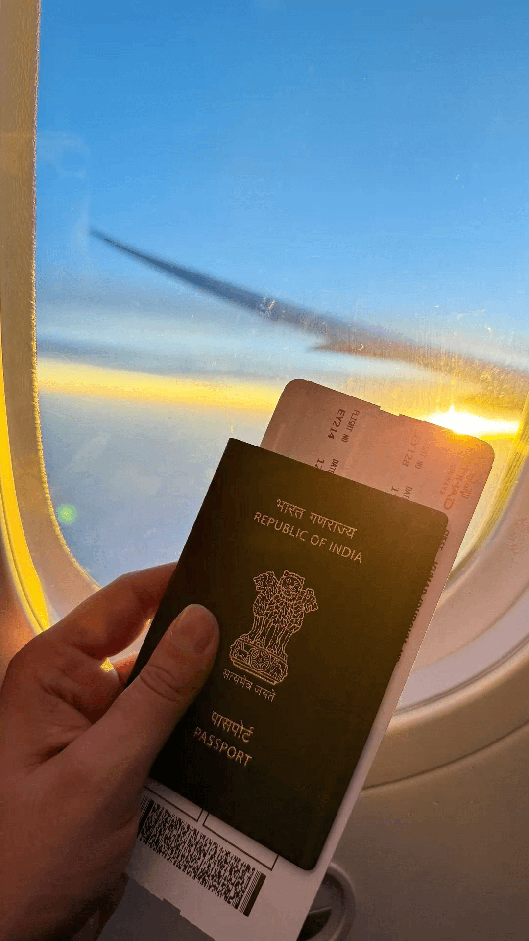 Passport and boarding pass held up at a plane window