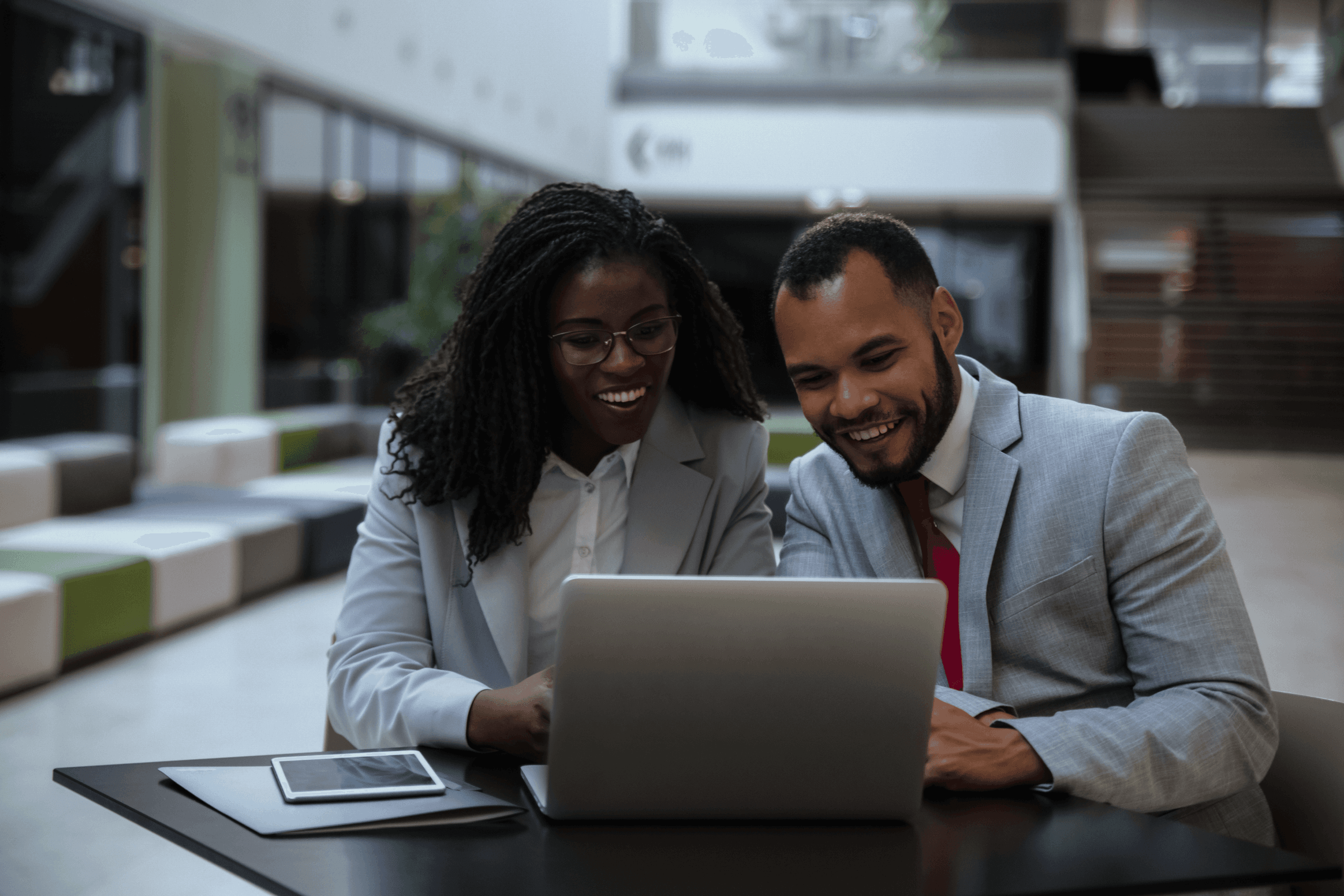 Two smiling professionals working together on a laptop